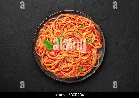 Spaghetti de tomate sur une assiette noire sur une table en ardoise sombre. Les pâtes à la sauce tomate sont des plats de cuisine italienne classiques. Cuisine italienne populaire. Vue de dessus Banque D'Images