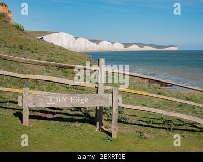 Seven Sisters falaises, East Sussex, Angleterre. Un panneau d'avertissement « Cliff Edge » sur la côte sud anglaise avec les falaises de craie blanches emblématiques visibles derrière. Banque D'Images