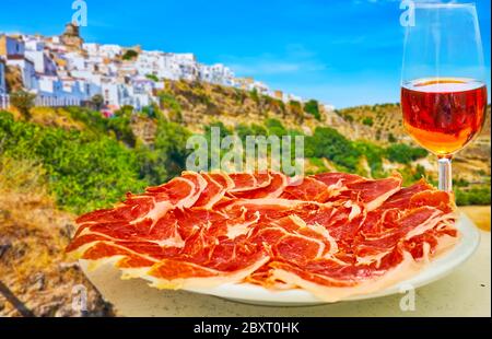 Dégustez le savoureux déjeuner espagnol - un verre de vin de sherry et de jambon Iberico (jambon sec) avec vue sur une colline rocheuse escarpée surmontée d'un blanc médiéval à Banque D'Images