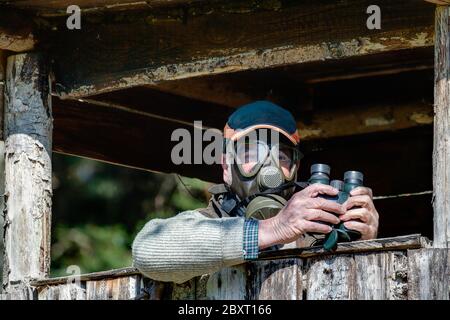 Un chasseur avec un masque gaz est assis sur son si ge haut et