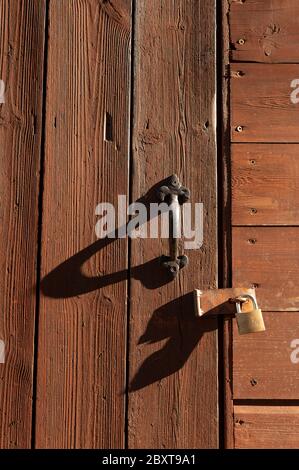 Porte en bois peint marron verrouillée par cadenas et longues ombres Banque D'Images