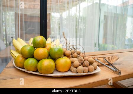 Fruits de longan, orange, banane, mis en plaque de bambou sur la table dans le champ extérieur. Banque D'Images