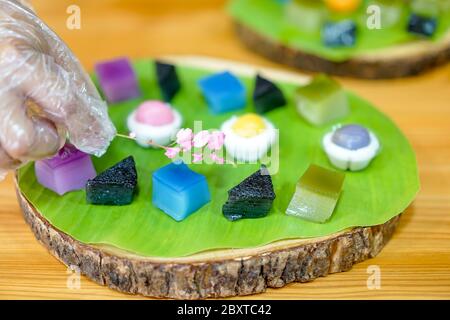 La main du chef thaïlandais est de décorer les variétés traditionnels desserts thaïlandais colorés ; farine vapeur, crème anglaise noire, crème de coco et haricots vapeur, couche Banque D'Images