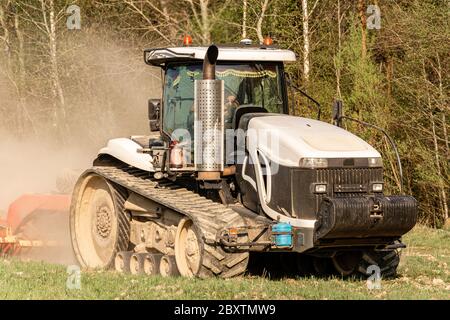 Au printemps, un agriculteur tire des herses avec un tracteur moderne et sème un champ avec des betteraves. Campagne de semis sur les terres agricoles pendant le travail du sol. Banque D'Images