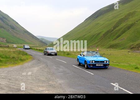 Moffat, Écosse - 29 JUIN 2019 : voiture bleue reliant Scimitar 1991 suivie d'une Mercedes-Benz 300 1981 dans un rallye automobile classique en route vers la ville Banque D'Images