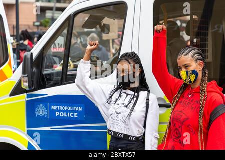 Deux jeunes manifestants élèvent leurs poings devant une camionnette de police lors de la manifestation Black Lives Matters à Vauxhall, Londres, le 6 juin 2020 Banque D'Images