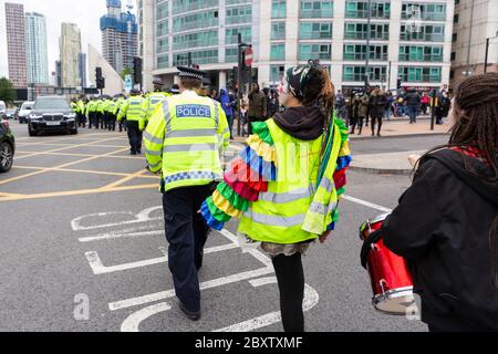 Une femme vêtue de robe de chambre et d'une veste haute visibilité frappe une ligne de policiers pendant la Black Lives Matters manifestation à Londres, le 6 juin 2020 Banque D'Images