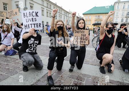 Les manifestants prennent le genou et tiennent leurs poings en main tout en tenant des pancartes anti-racisme pendant la manifestation Black Lives Matter.des centaines de jeunes ont participé à la manifestation « Black Lives Matter » à Cracovie, la plus grande ville du sud de la Pologne. Ils ont rendu hommage à George Floyd et ont exprimé leur désapprobation de la brutalité policière et du racisme. Banque D'Images