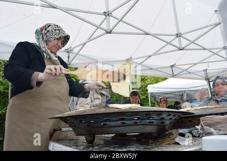 Bucarest, Roumanie. 22 mai 2016. Une femme turque fait basculer du pain plat turc sur un four saj, au Festival turc de Bucarest. Banque D'Images