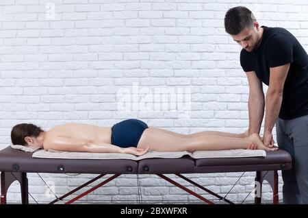 Jeune femme recevant un massage séesion à la maison par un physiothérapeute. Banque D'Images