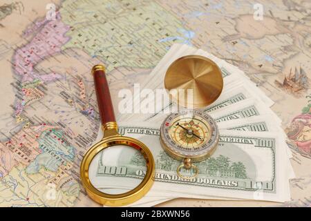 Un ensemble de dollars américains se trouve avec une boussole et une loupe sur la carte du monde Banque D'Images