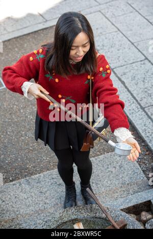 Une japonaise se lavant les mains et versant de l'eau à sa main pour la laver au sanctuaire Kiyomizu-dera à Kyoto, au Japon Banque D'Images