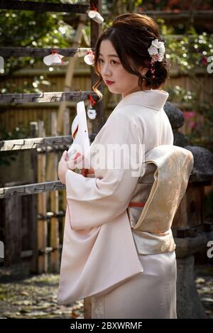 L'adolescent japonais portant un kimono traditionnel pose avec un masque de kitsune. Masque de renard japonais. Ces masques sont portés pour le plaisir, lors des festivals et pour honorer les dieux Banque D'Images