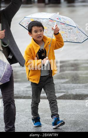 Un garçon japonais tenant un parapluie un matin pluvieux au sanctuaire Meiji à Tokyo, au Japon Banque D'Images