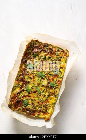Concept alimentaire. Omelette cuite au four avec courgettes, poireaux et fromage isolés sur fond blanc. Vue de dessus. Banque D'Images