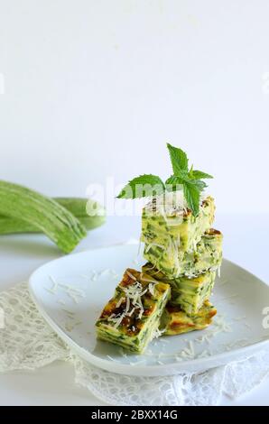 Concept alimentaire de printemps. Courgettes maison et frittata de poireaux arrosées de parmesan, saveur de menthe. Gros plan. Fond blanc. Banque D'Images