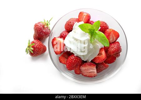 Dessert de fraises fraîches, crème fouettée et garniture de menthe poivrée dans un bol en verre, isolé avec des ombres sur fond blanc, vue en grand angle fr Banque D'Images