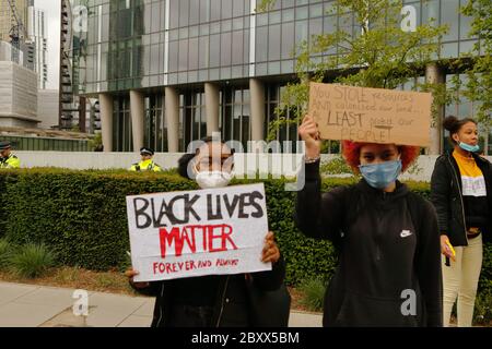 Deux jeunes activistes portant un masque facial tiennent des plaques devant l'ambassade américaine pendant la marche de la Black Lives Matter (BLM) de Londres pour protester contre poli Banque D'Images