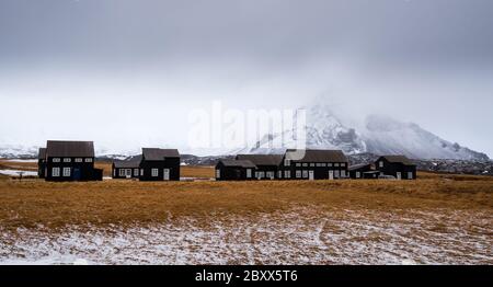 Petites maisons de cabine et la montagne enneigée de Stapafel à Hellnar, péninsule de Snaefellnes en Islande Banque D'Images