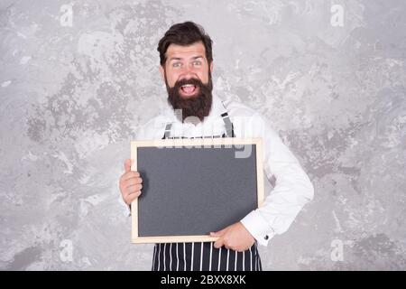 publicité de votre produit. hipster cook ou barista présentant le produit. sentez le succès. menu du café. cuisine ravie. cuisine du chef de restaurant. barbu brutal avec tableau noir. Banque D'Images