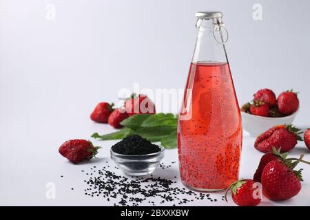 Buvez des fraises saines avec des graines de basilic dans une bouteille sur fond blanc, gros plan, espace de copie Banque D'Images