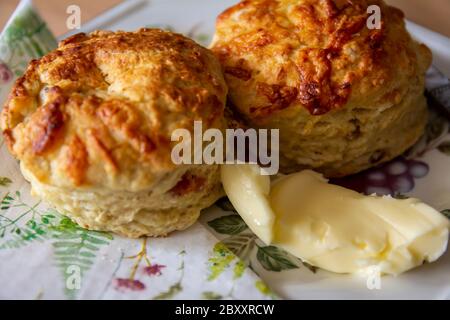 Deux scones au bacon et au fromage sur une assiette avec serviette et une portion de beurre Banque D'Images