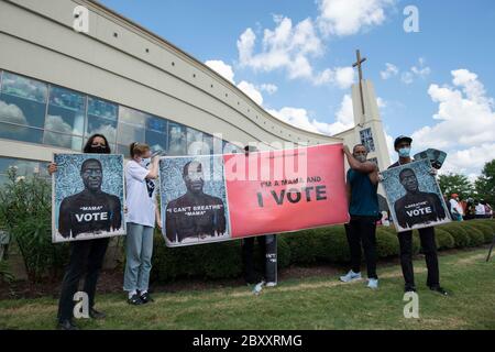 Les manifestants présentent des panneaux avec des photos de George Floyd devant l'église de la Fontaine de louange, où des milliers de personnes ont attendu la file pour assister à la visite publique de Floyd dans la banlieue de Houston. La mort de Floyd, causée par un policier blanc, a déclenché des manifestations mondiales contre le racisme et la brutalité policière. Banque D'Images