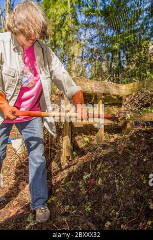 Femme tournant un tas de compost avec une fourchette de compost. Ce tas de compost est en excellente forme pour commencer le compostage, car il a été créé à partir d'un égal A. Banque D'Images