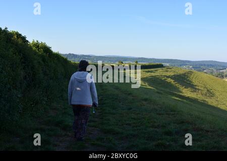 Femme marchant sur le sentier de Donkey Lane, regardant le long de la crête vers Sherborne au loin, Dorset, Angleterre Banque D'Images