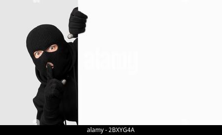 Voleur masqué qui a fait un coup de tête sur un tableau blanc, faisant un signe de hush Banque D'Images