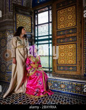 FÈS, MAROC - VERS MAI 2018 : jeunes marocaines vêtues de robes traditionnelles assises par une fenêtre à Fès Banque D'Images