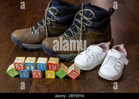 message de fête des pères heureux écrit avec des blocs de bois pour enfants avec des chaussures pour adultes et pour enfants en arrière-plan Banque D'Images