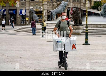 Skopje, Macédoine du Nord. 8 juin 2020. Un homme portant un masque de visage fait un scooter électrique sur la place principale de Skopje, capitale de la Macédoine du Nord, le 8 juin 2020. Crédit: Tomislav Georgiev/Xinhua/Alay Live News Banque D'Images