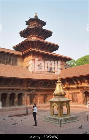 Une jeune femme se tient à Mul Chowk, une sorte de cour dans le complexe du palais royal, la place Durbar, Patan (Lalitpur), la vallée de Katmandou, Népal Banque D'Images