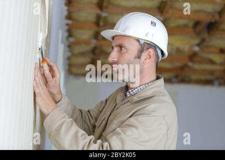 homme constructeur enlever l'ancien papier peint Banque D'Images