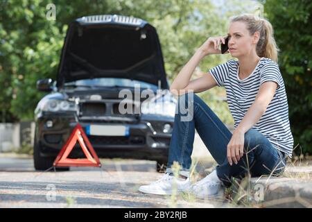 jolie femme au téléphone ayant un problème avec la voiture Banque D'Images