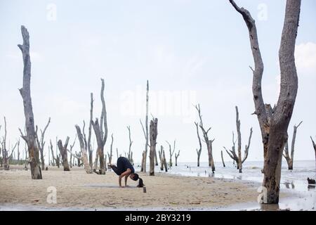 Portrait de jeune asiatique yogi femme attrayante avec ses yeux fermés dans la posture méditante, exercice de détente, l'entraînement, le port de vêtements de sport, haut noir Banque D'Images