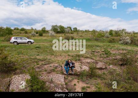 Vue aérienne d'un jeune couple dans la nature embrassant et passant du temps avec la voiture, rochers en arrière-plan Banque D'Images