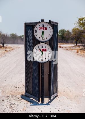 Porte du camping avec heure d'ouverture et de fermeture marquée (Halali, Parc national d'Etosha, Namibie) Banque D'Images