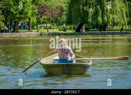 Bucarest/ Roumanie - 05.30.2020: Homme sur un bateau pagayer. Homme profitant d'un agréable jour d'été ou de printemps dans le parc Cismigiu, Bucarest Banque D'Images