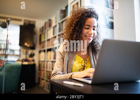 Belle femme heureuse utilisant l'ordinateur portable. Étude, apprentissage, concept universitaire Banque D'Images