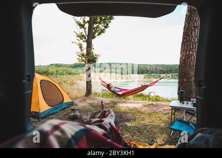 vue sur la personne couple se reposant au camping femme pontant dans hamac avec belle vue sur le lac forestier Banque D'Images