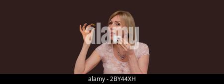 Belle femme avec une tasse de thé ou de café. Portrait studio d'une femme blonde rêveuse , tenant une tasse de café et de chocolat dans ses mains, buvant de la crème Banque D'Images