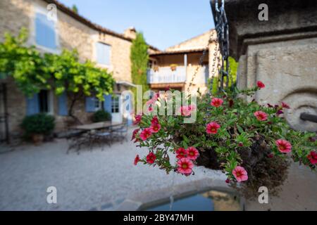 Paniers suspendus sur une fontaine dans la cour d'une maison typique en Provence, France Banque D'Images