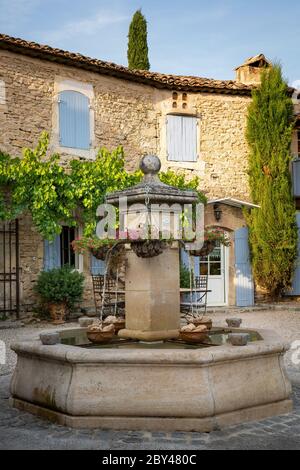 Paniers suspendus sur une fontaine dans la cour d'une maison typique en Provence, France Banque D'Images