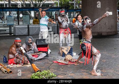 Touristes posant pour une photo avec des artistes de rue aborigènes, Circular Quay, Sydney, Nouvelle-Galles du Sud, Australie Banque D'Images