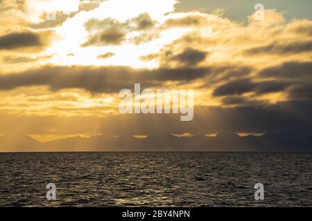Coucher de soleil dans 'Icefjord' sur le Spitsbergen avec des poutres de soleil et des montagnes à l'horizon Banque D'Images