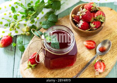 Concept de conservation maison. Sirop de fraise et baies de fraise fraîches sur une table en bois. Banque D'Images
