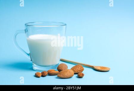 Lait d'amande dans un verre sur fond bleu avec noix Banque D'Images