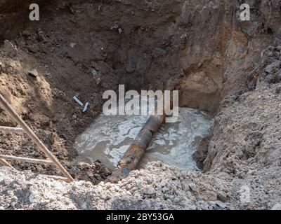 rupture d'un pipeline d'eau rouillée endommagé dans une tranchée profonde. processus de réparation des infrastructures de la ville Banque D'Images